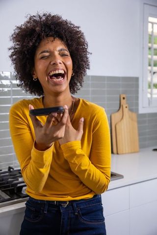 Joyful Woman Enjoying Voice Chat in Kitchen