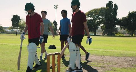 Teen cricket players walking off field after match, teammates directing play