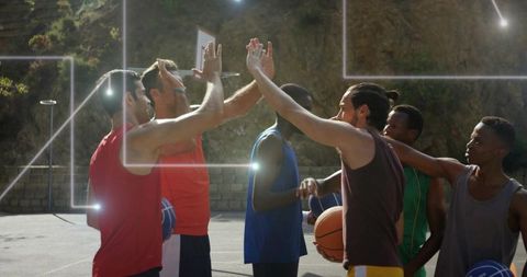 Energetic basketball players celebrating victory with high-fives outdoors