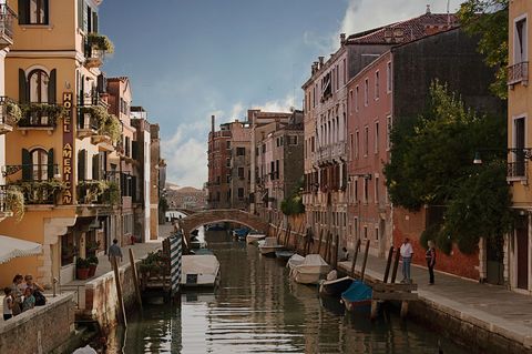 Venice canal with historic pastel buildings, arched bridge and boats reflecting golden light
