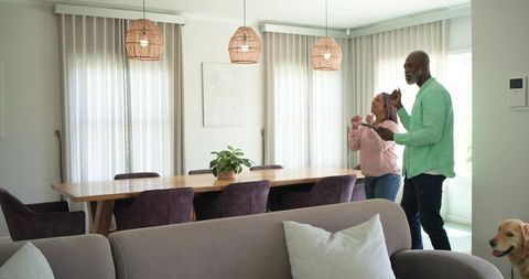 Couple enjoying slow dance in cozy open-plan living and dining room with natural light