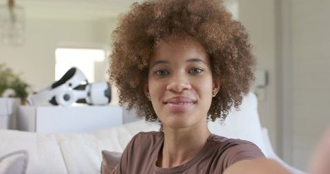 Young african american woman taking selfie on sofa while unpacking vr headset boxes