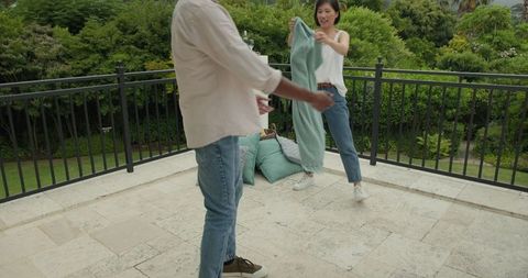 Couple Setting Up Outdoor Picnic with Blanket and Cushions
