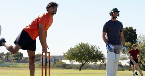 Underarm bowler appealing at stumps with batsman and diverse team on local cricket ground