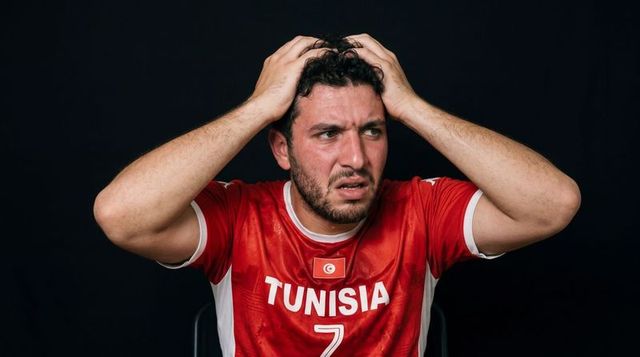 Tunisian soccer fan gripping hair in distress wearing number 7 jersey at intense match