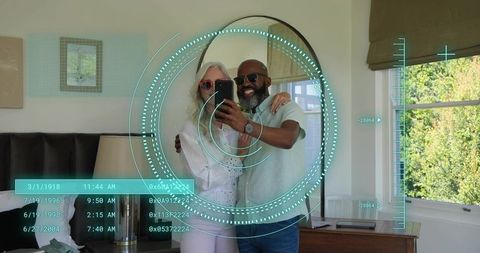 Mature couple taking augmented reality mirror selfie with futuristic hud in bedroom