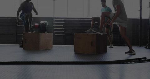 Three men performing box jumps and step-ups during intense group gym workout
