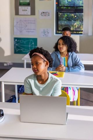 African American Students Using Laptop and Taking Notes in Bright Classroom