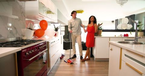 Couple Cleaning Festive Aftermath in Modern Kitchen