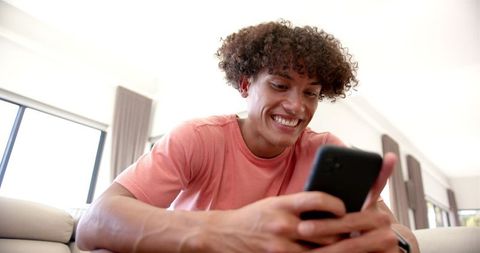 Cheerful Young Man Engaging with Smartphone at Home