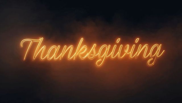 Glowing Thanksgiving Neon Script Sign Casting Warm Amber Light Through Smoky Fog Backdrop