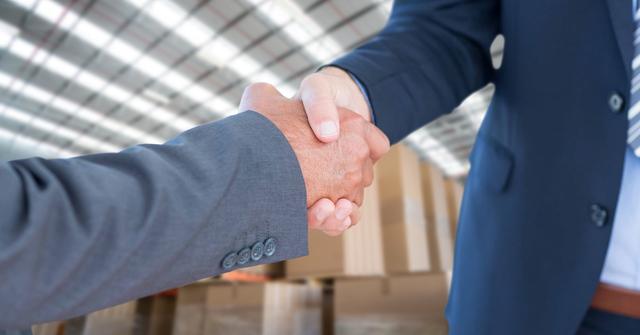 Digital composite of Business people shaking hands in warehouse