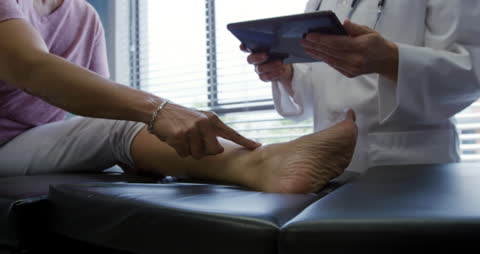 Doctor Examining Ankle with Tablet During Physiotherapy Session