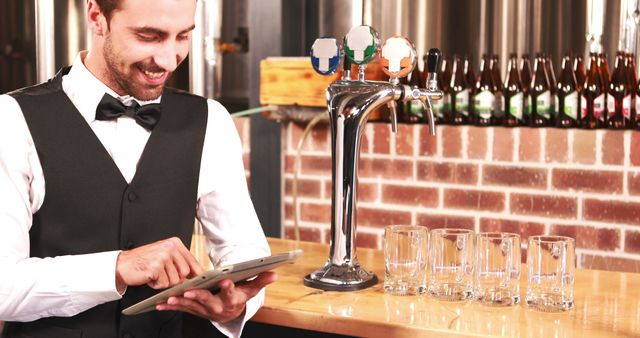 Smiling barkeeper using tablet well dressed at bar - Download Free Stock Photos Pikwizard.com