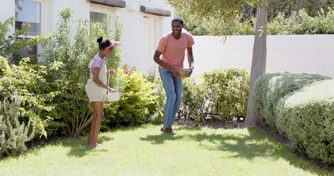Father and Daughter Enjoying Easter Egg Hunting on Sunny Day