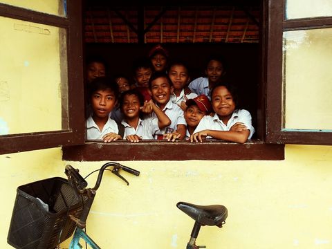 Group of happy school children smiling through window