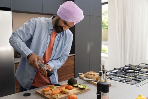 Man with turban preparing avocado toast in modern kitchen