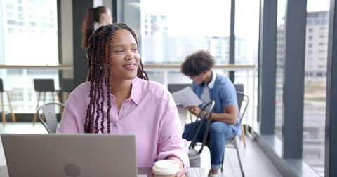 Smiling Woman Enjoying Coffee While Working in Modern Office