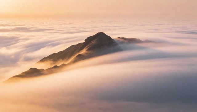 Dark Mountain Ridge Piercing Sea of Clouds at Golden Sunrise, Misty Alpine Panorama