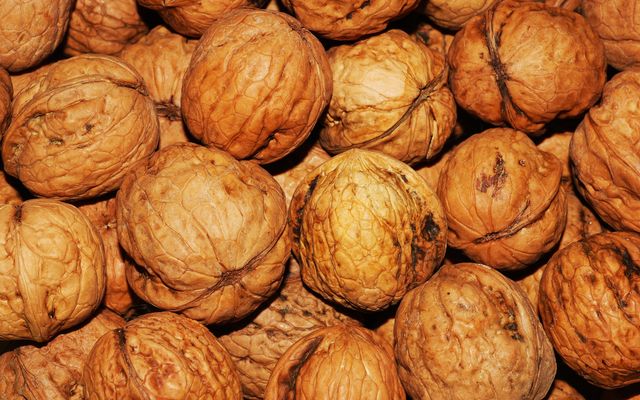Brown walnuts piled together without shells; ideal for illustrating healthy eating, natural snacks, organic diets, textured backgrounds, or nutritional information. Great for use in food blogs, health articles, or dietary guides.