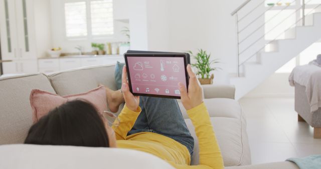 Relaxed Asian Woman Using Tablet on Couch in Sunny Living Room - Download Free Stock Images Pikwizard.com