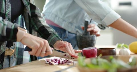 Friends chopping red onion using mortar and pestle during casual home cooking