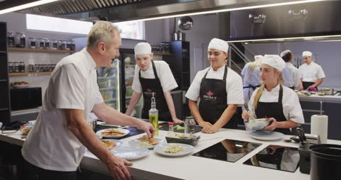 Chefs Collaborating in Professional Kitchen During Cookery Class