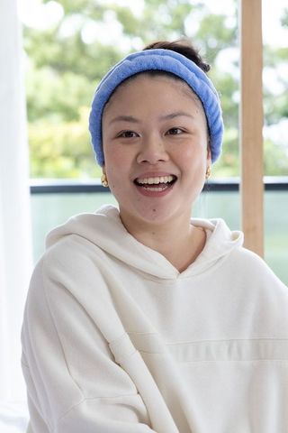 Asian woman smiling speaking wearing blue headband white hoodie casual lifestyle portrait