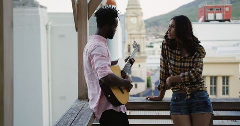 Diverse Friends Enjoying Music on Rooftop at Dusk
