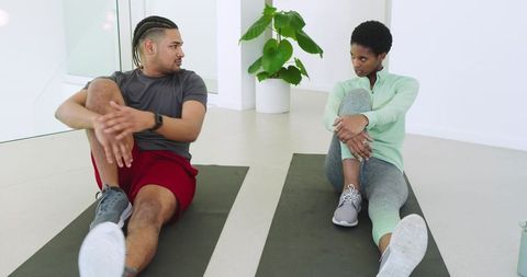 Diverse athletes performing seated stretch exercises indoors