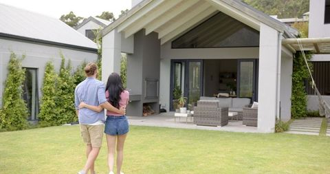 Young Couple Admiring New Home from Backyard