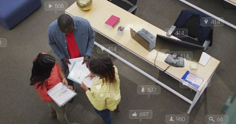 Overhead view of team collaborating around desk with clipboards in open-plan office