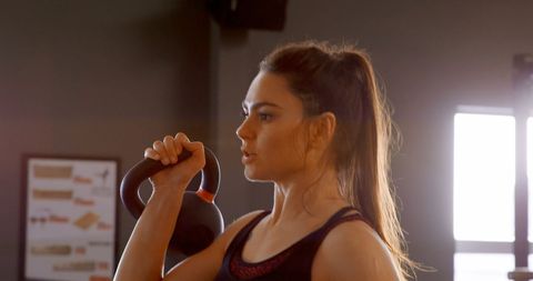 Energetic Woman Engaging in Kettlebell Workout at Fitness Studio
