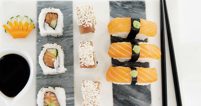Assorted sushi pieces are elegantly arranged on a slate with soy sauce and chopsticks to the side, with copy space. Sushi, a traditional Japanese dish, is enjoyed worldwide for its fresh flavors and artistic presentation.