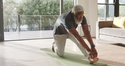 Mature Man Stretching on Yoga Mat at Home in Natural Light