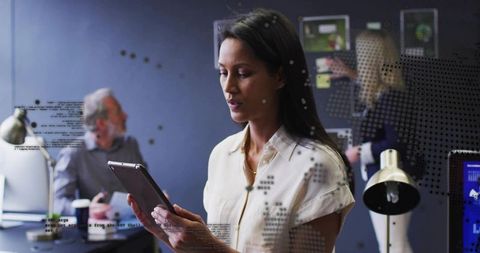 Professional woman holding tablet and reading digital screen in modern collaborative office