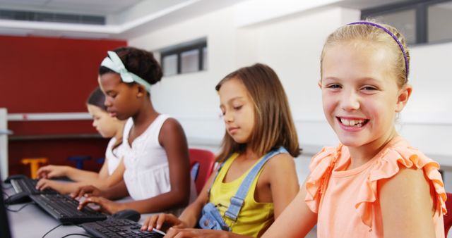 Diverse group of young, happy students using computers in a classroom setting. The children are engaged in their work, highlighting themes of teamwork, education, and familiarity with technology from a young age. Perfect for educational content, school advertisements, and technology in education promotions.