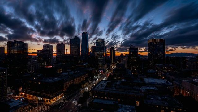 Central tower looming over downtown at dusk with streaking clouds and glowing streets