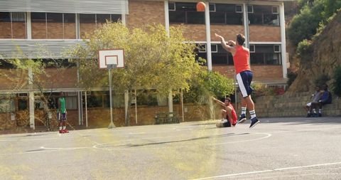 Young athlete shooting basketball on sunlit outdoor court