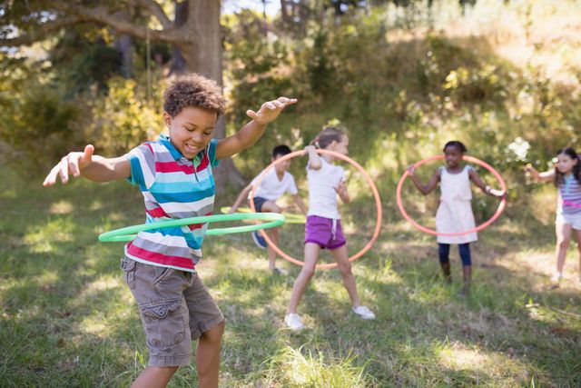 Group of friends enjoying with hula hoops on grassy field at campsite