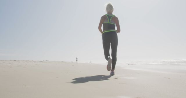Senior caucasian woman wearing sports clothes and running at beach. Retirement, free time, healthy and active lifestyle.