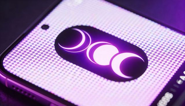 Neon triple moon symbol glowing on smartphone display with purple ambient light