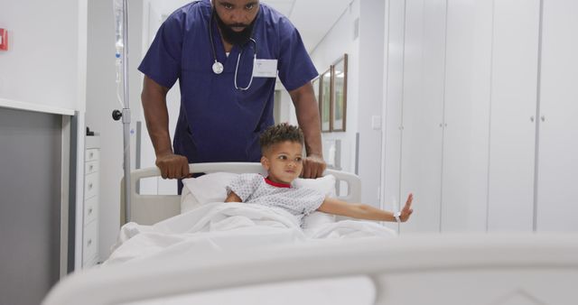 African american male doctor walking with child patient laying in bed at hospital. Medicine, healthcare, lifestyle and hospital concept.