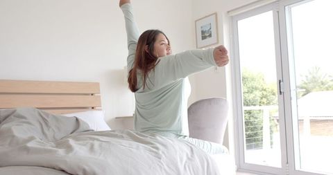 Woman Stretching in Morning Sunlight Bedroom Wakeup