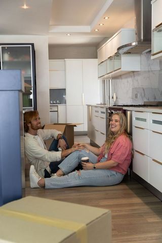 Happy Couple Enjoying Coffee Break While Unpacking in New Kitchen