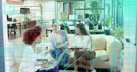 Three women collaborating in modern office lounge with digital data overlay