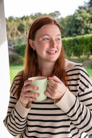 Young Woman Relaxing on Porch with Mug in Natural Garden Setting