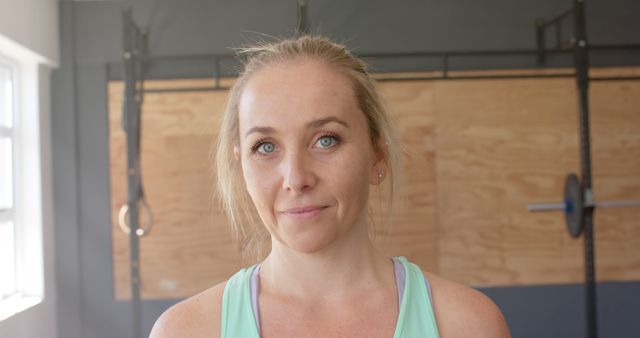 Portrait of happy caucasian woman with blonde hair and blue eyes at gym. Fitness and healthy lifestyle, unaltered.