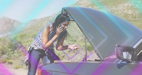 Indian woman calling for roadside help while checking car engine on rural mountain road