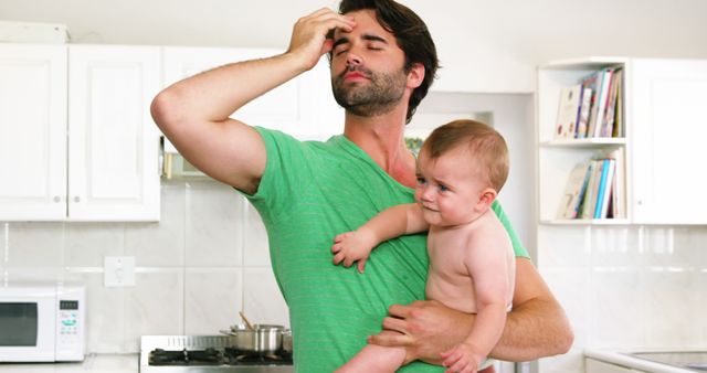 Father holding his baby and have a headache at home